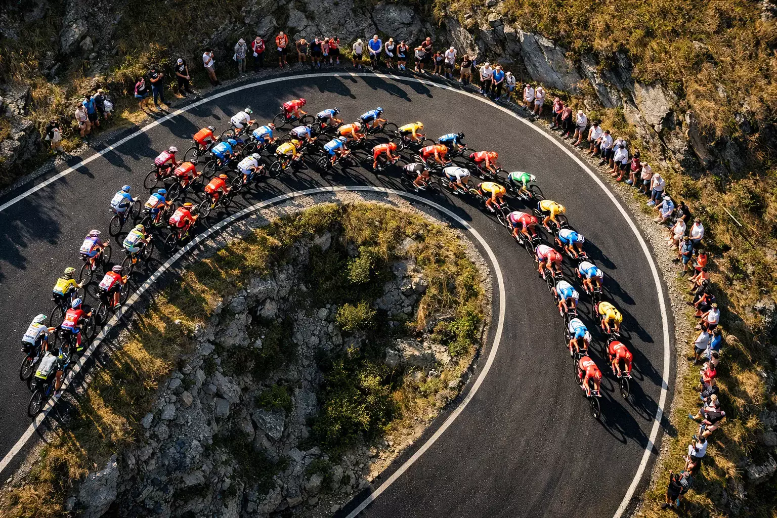 Vue plongeante sur un peloton de cyclistes traversant un virage serré lors d'une course professionnelle